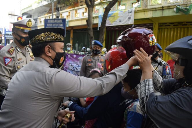 
Polisi di Pasuruan Bagikan Masker dan Helm untuk Pengendara yang Terjaring Prokes